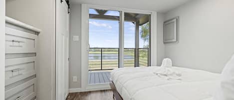 Un dormitorio con cama, armario y balcón con vistas al exterior.