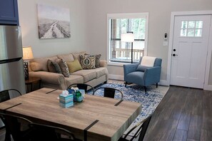 A living room with a sofa, armchair, coffee table, and a dining table with chairs. - Outstanding Cabin Incredible for Six People in Livingston, Texas (Livingston)