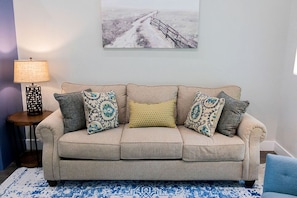 A beige sofa with patterned cushions, a small side table with a lamp, and a painting on the wall. - Outstanding Cabin Incredible for Six People in Livingston, Texas (Livingston)