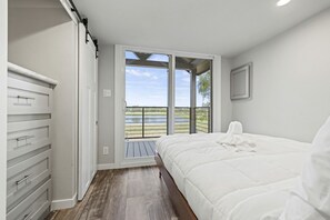 A bedroom with a bed, a wardrobe, and a balcony with a view of the outdoors. - Pet-Friendly Cabin with Lofted Interior and Water Views in Texas (Fredericksburg)