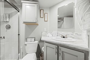 A bathroom with a shower, toilet, sink, and cabinet. - Pet-Friendly Cabin with Lofted Interior and Water Views in Texas (Fredericksburg)