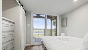 Un dormitorio con cama, armario y balcón con vistas al exterior.