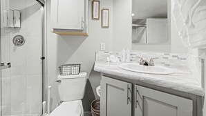 Une salle de bain équipée d’une douche, de toilettes, d’un lavabo et d’un meuble de rangement.
