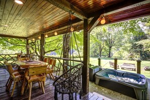 A wooden deck with a table and chairs, a hot tub, and a view of a wooded area. - Incredible Cabin with Hot-tub, Fire Pit and Petting Zoo in Sugar Grove, North Carolina (Sugar Grove)