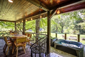 A wooden deck with a table and chairs, a hot tub, and a view of a wooded area. - Incredible Cabin with Hot-tub, Fire Pit and Petting Zoo in Sugar Grove, North Carolina (Sugar Grove)