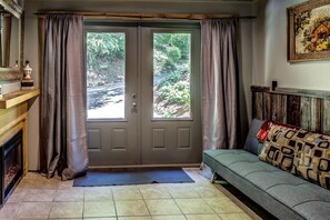 A room with a double door, a fireplace, a sofa with patterned cushions, and a painting on the wall. - Incredible Cabin with Hot-tub, Fire Pit and Petting Zoo in Sugar Grove, North Carolina (Sugar Grove)