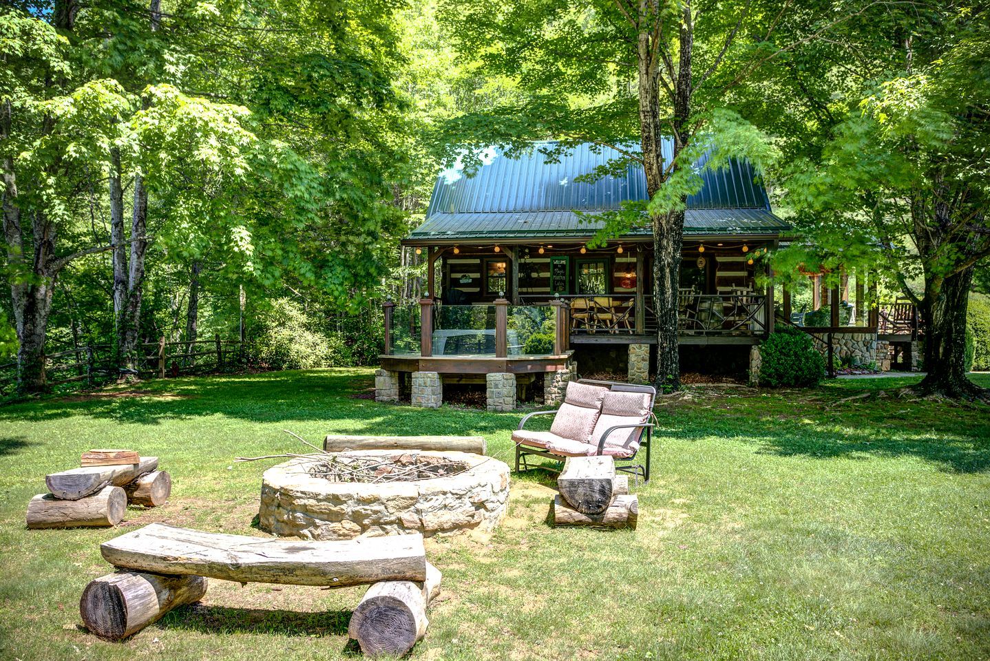 A rustic cabin with a stone fire pit, outdoor seating, and a covered deck.