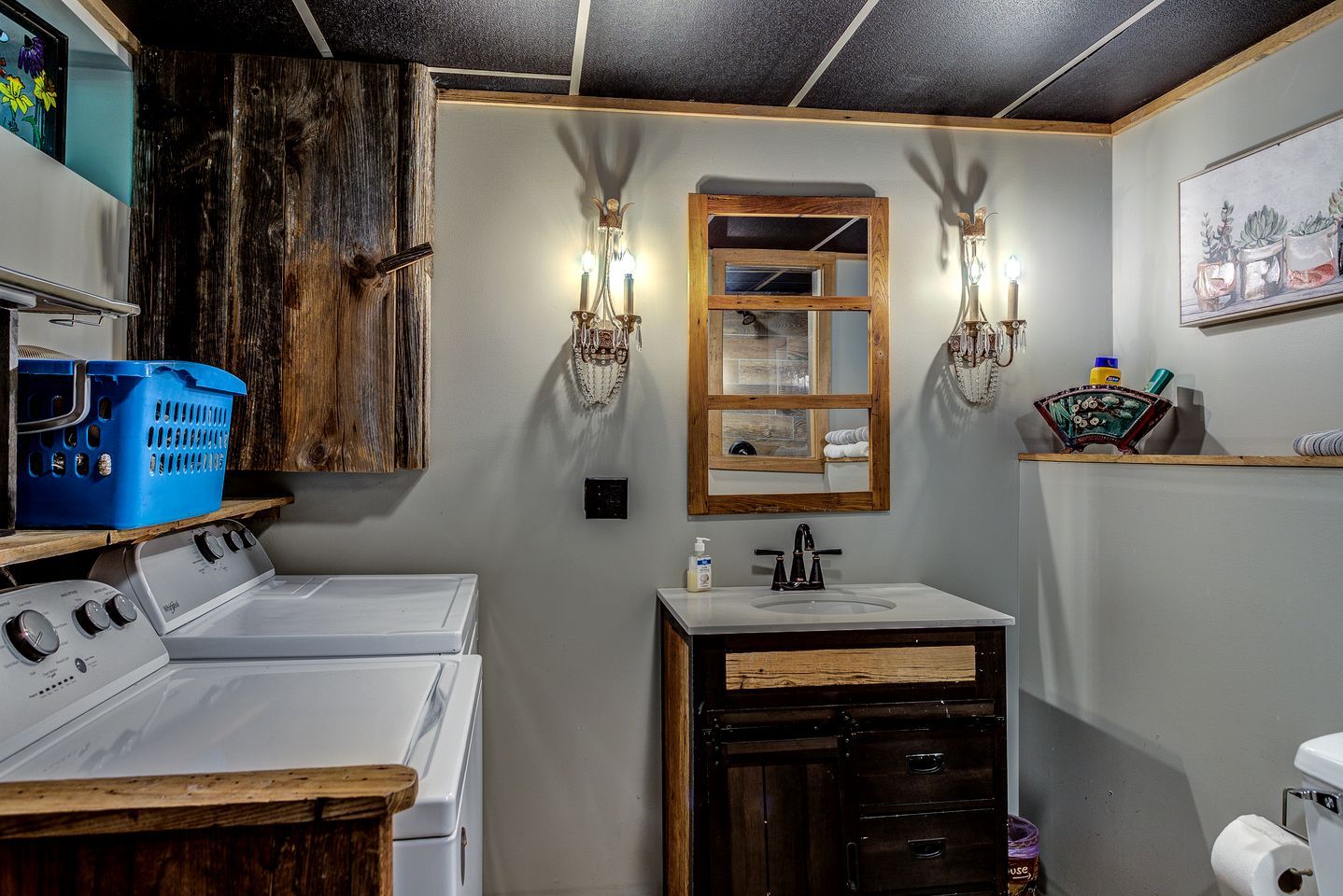 A laundry room with a washing machine, dryer, wooden cabinets, and a sink with a mirror.