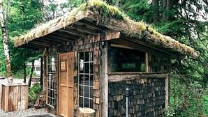 A rustic cabin with a thatched roof, wooden walls, and a small porch area.