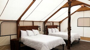 A tent with two beds, wooden beams, and a simple, functional design.