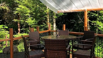 A wooden deck with a table and chairs, surrounded by a white canopy.