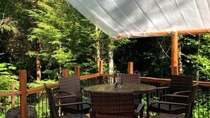 A wooden deck with a table and chairs, surrounded by a white canopy.