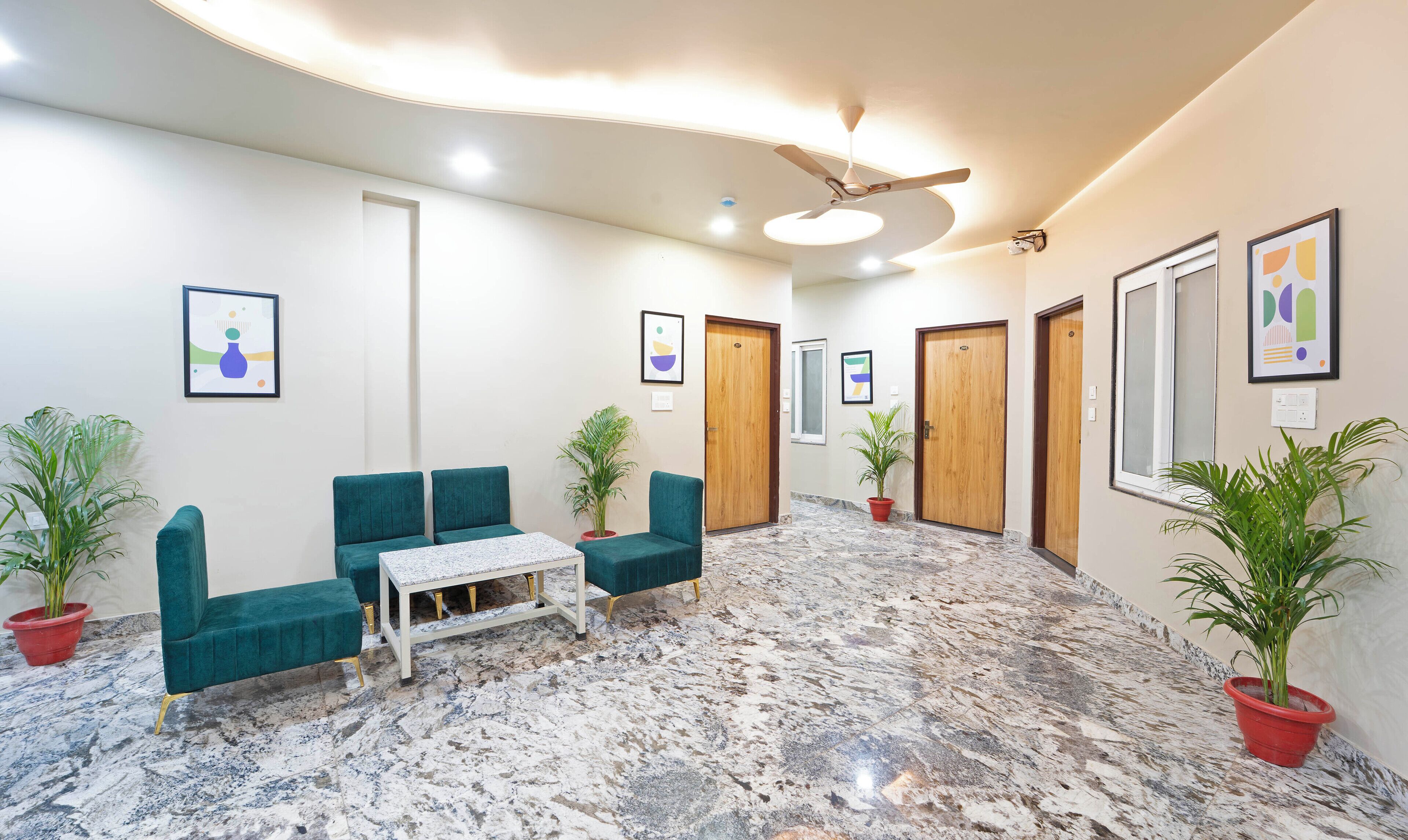 A lobby with teal sofas, a marble floor, and wooden doors.