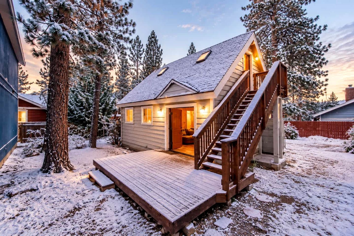 Une cabane en bois avec un escalier, entourée d’arbres couverts de neige.