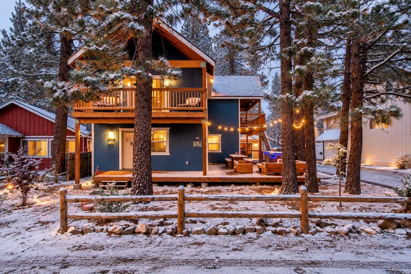 Une cabane à deux étages dotée d’un balcon, entourée d’un paysage enneigé et d’arbres.