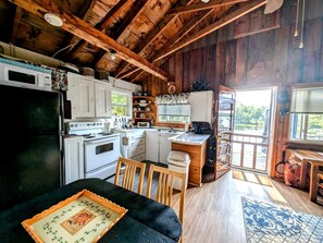 A rustic cabin interior with a kitchen, dining area, and a view of the outdoors. - Gorgeous Waterfront Cabin for an Unforgettable Family Vacation by Georges Pond in Franklin, Maine (Franklin)