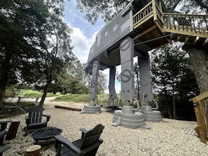 A large mechanical structure resembling a robot, a wooden deck, and outdoor seating.