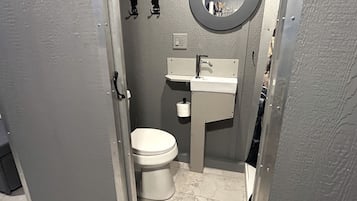 Une petite salle de bain comprenant des toilettes, un lavabo et un miroir.