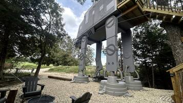 A large mechanical structure resembling a robot, a wooden deck, and outdoor seating.