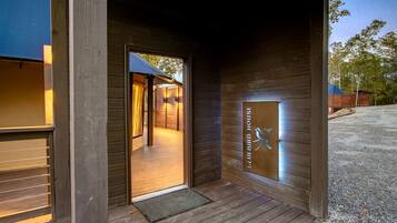 A wooden exterior with a door leading to an interior space, a metal plaque with a bird design, and a gravel driveway.