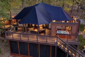 Eine Hütte mit Terrasse, Sitzgelegenheiten im Freien, einer Feuerstelle und einem Whirlpool.