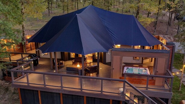 Una cabaña con terraza, asientos exteriores, una chimenea y un jacuzzi.
