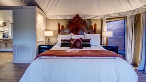 Un dormitorio amplio con una cama grande, un cabecero de madera, lámparas de noche y vistas a una terraza de madera.