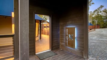 A wooden exterior with a door leading to an interior space, a metal plaque with a bird design, and a gravel driveway.
