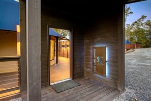 A wooden exterior with a door leading to an interior space, a metal plaque with a bird design, and a gravel driveway.