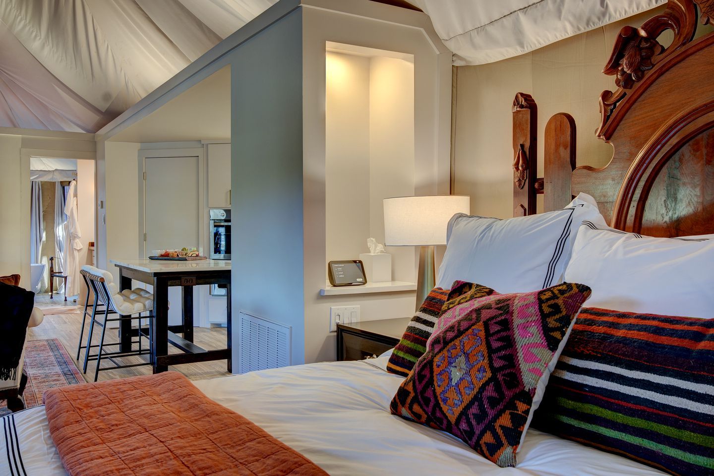 A hotel room with a bed, a desk, a chair, a lamp, and a wall-mounted clock.