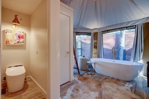 Ein Badezimmer mit einer Badewanne, Holzboden, Teppich und einem Bild an der Wand.