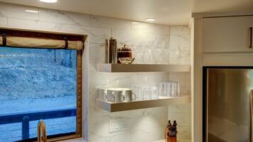 A modern kitchen with marble countertops, a built-in wine cooler, and a stainless steel refrigerator.
