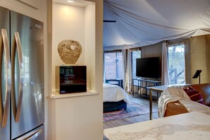 Une chambre d’hôtel moderne équipée d’un grand téléviseur à écran plat, d’un lit, d’un canapé et d’un coin repas.