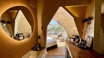 A tented accommodation with a bed, a sink, and a dining area.