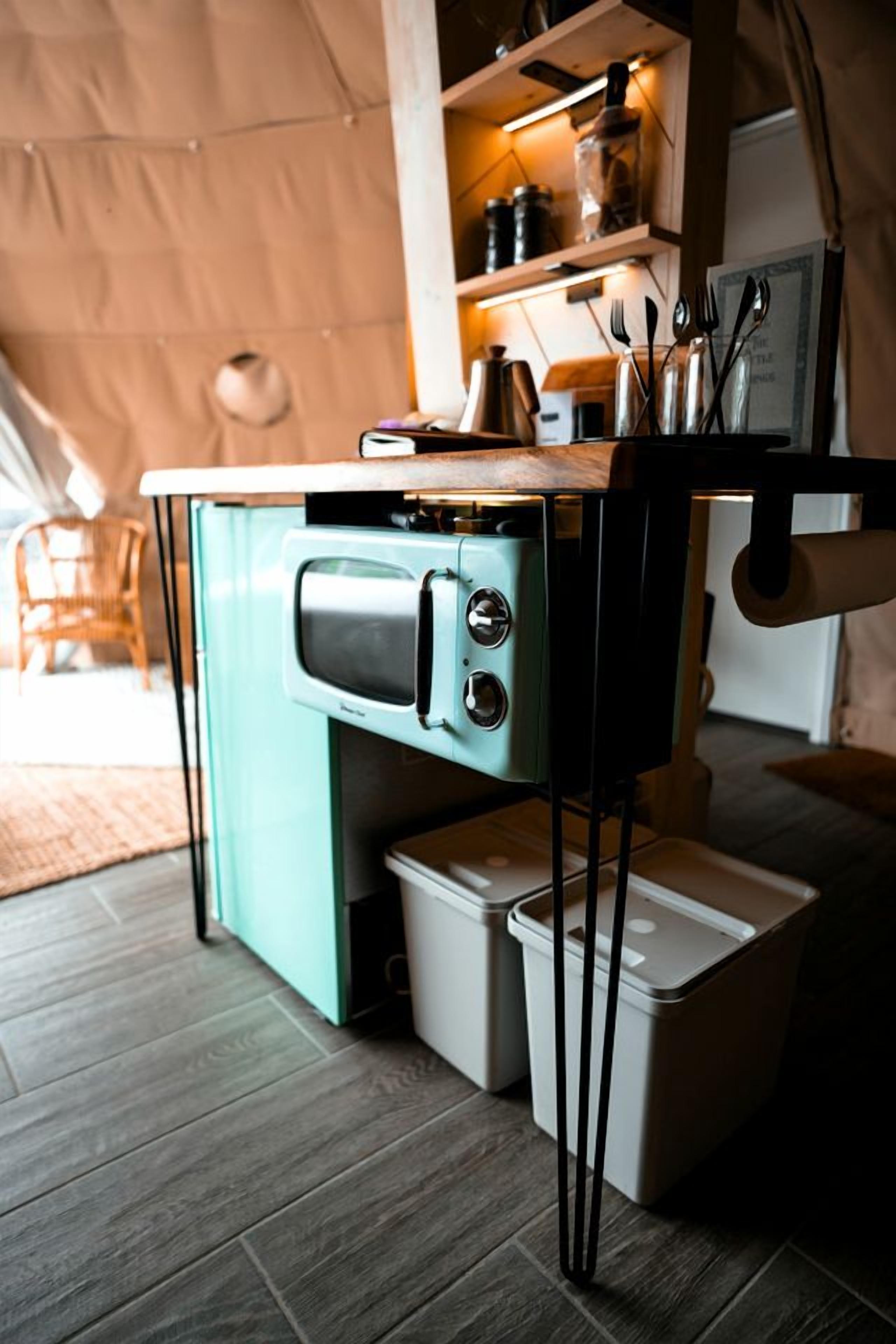 A compact kitchenette with a built-in oven, a coffee maker, and a small trash bin.