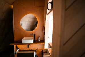 Ein Badezimmer mit einem runden Spiegel, einem weißen Waschbecken und einem Handtuchhalter.