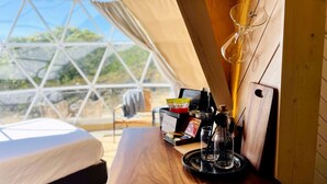 Une tente accueillante avec une table en bois, une cafetière en verre et une pancarte sur laquelle on peut lire : « INN YOU ».
