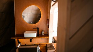 Une salle de bain avec un miroir rond, un lavabo blanc et un porte-serviettes.