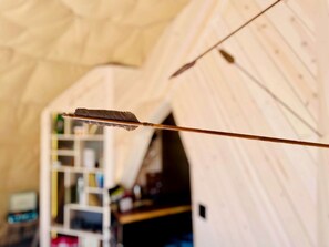 Een tent met houten inrichting, een schuin dak en een ladder op de achtergrond.