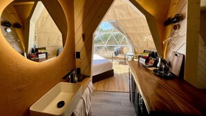 Un hébergement sous tente comprenant un lit, un lavabo et un espace repas.