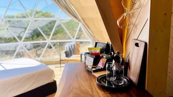 A cozy tent with a wooden table, a glass coffee pot, and a sign reading 'INN YOU'.