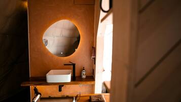 A bathroom with a round mirror, a white sink, and a towel rack.