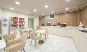 Ein modernes Café mit Marmorboden, beigen Stühlen, einer Kaffeestation und einem Snackregal.