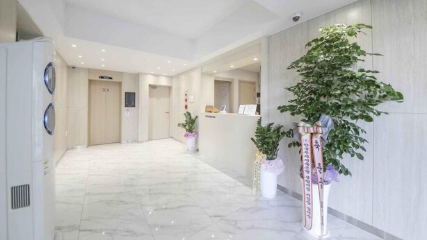 A hotel lobby with a marble floor, reception desk, and potted plants. - Hey Jecheon Hotel (Jecheon)