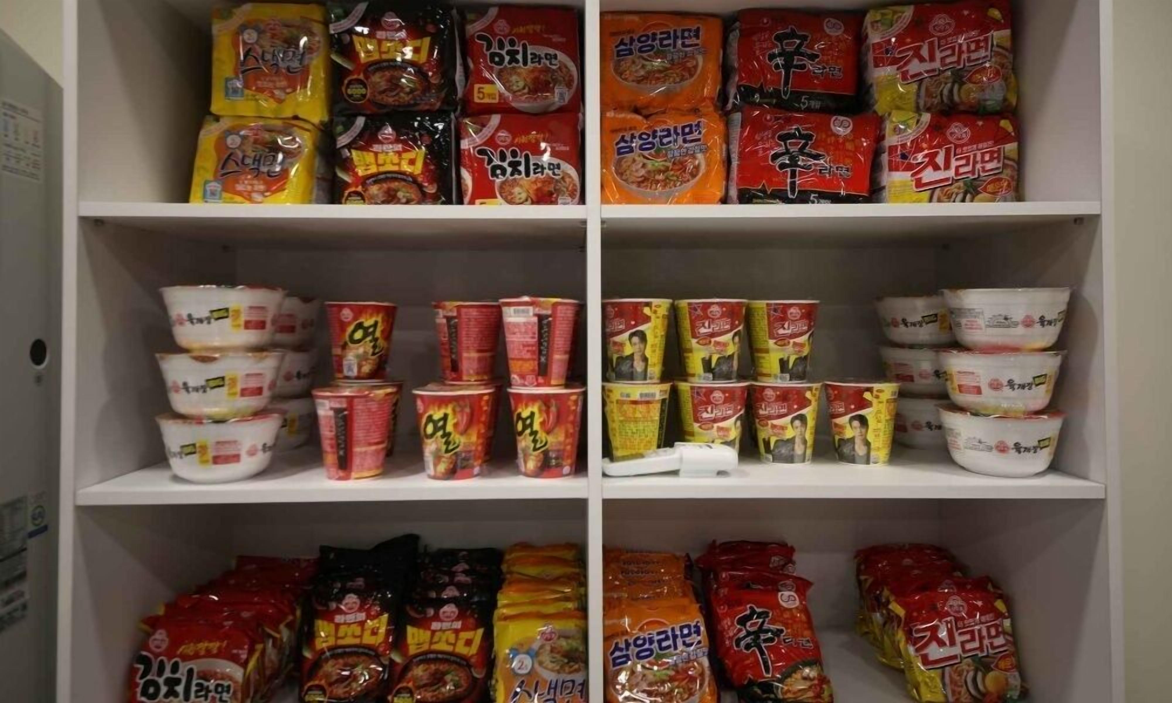 A pantry shelf stocked with various food items including packaged meals, canned goods, and condiments.