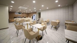 A modern dining area with marble flooring, beige chairs, and white tables. - Hey Jecheon Hotel (Jecheon)