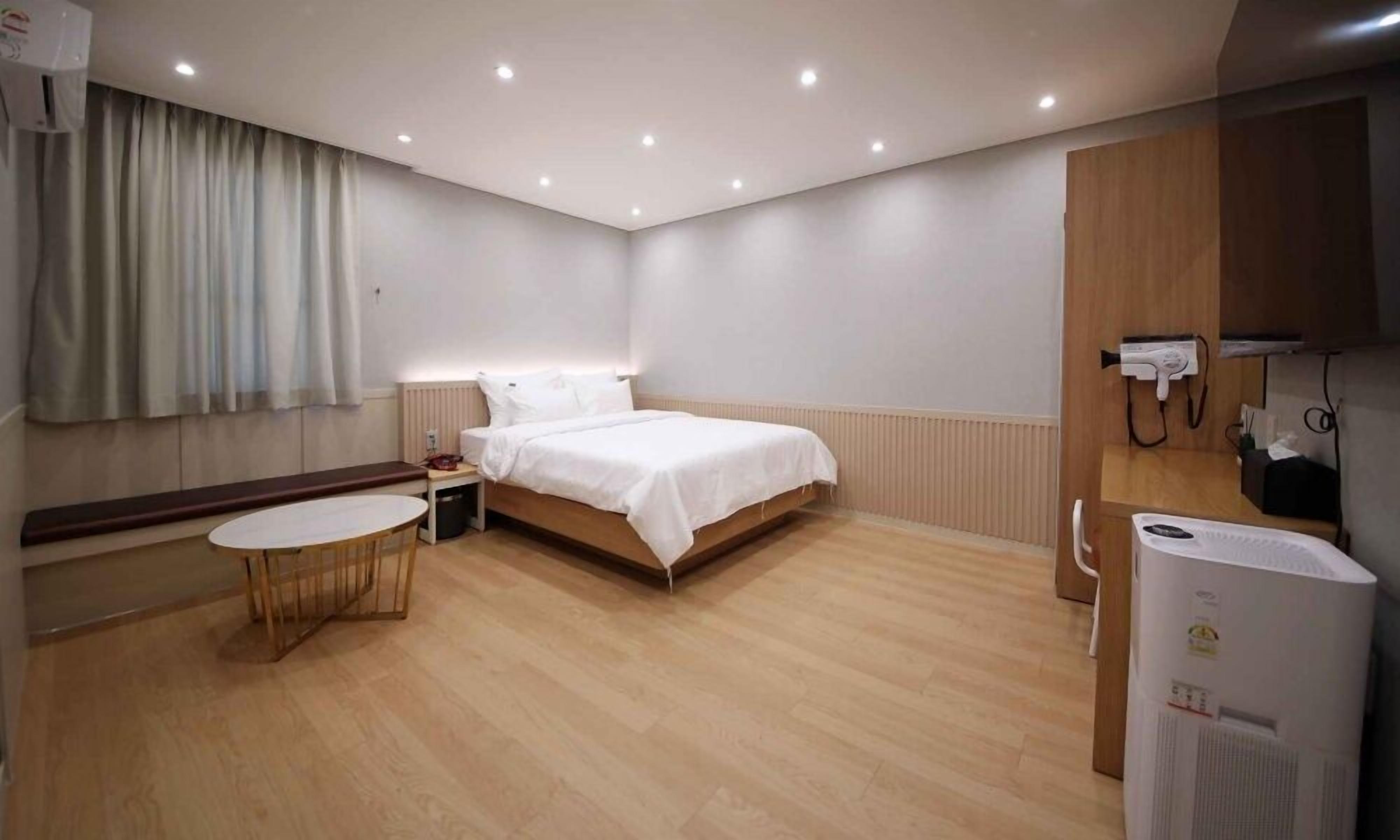 Habitación de hotel con cama, una mesita, una silla, un escritorio, un calentador y un teléfono.