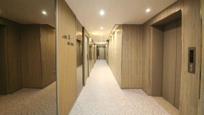 A hotel hallway with wooden paneling, numbered doors, and a carpeted floor. - Hey Jecheon Hotel (Jecheon)