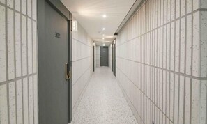 Ein Korridor mit gefliesten Wänden und einem gefliesten Boden, der zu einer Tür mit der Nummer 302 führt.