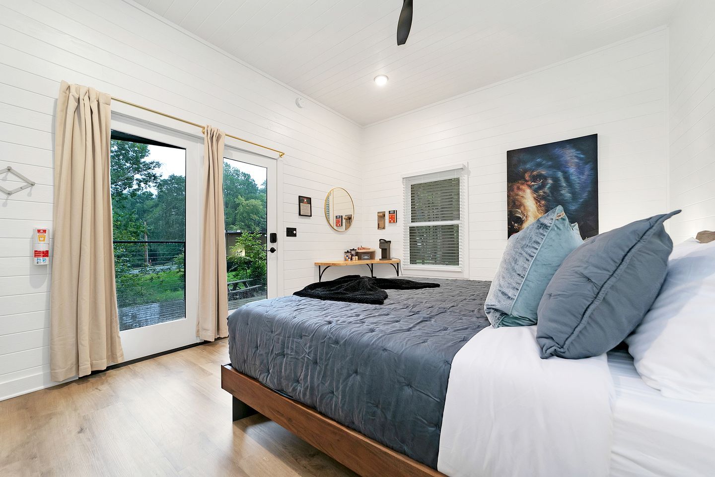 Een slaapkamer met een bed, een raam, een deur en een schilderij aan de muur.